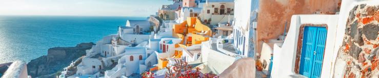 Santorini, Greece. Picturesq view of traditional cycladic Santorini houses on small street with flowers in foreground. Location - Oia village, Santorini, Greece. Vacations background_hero@1950x455